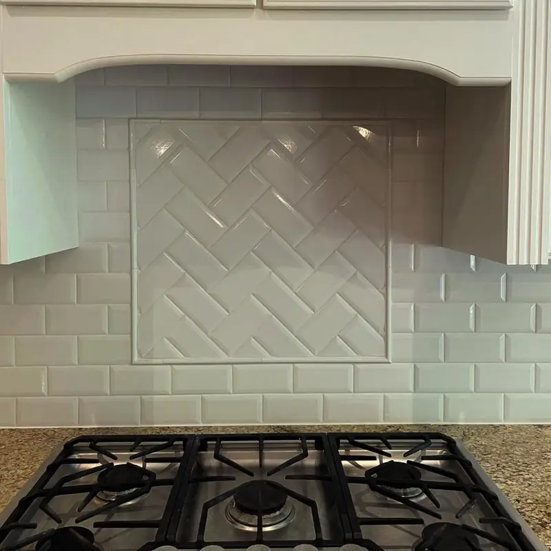 Subway tile backsplash with a herringbone panel behind a gas cooktop