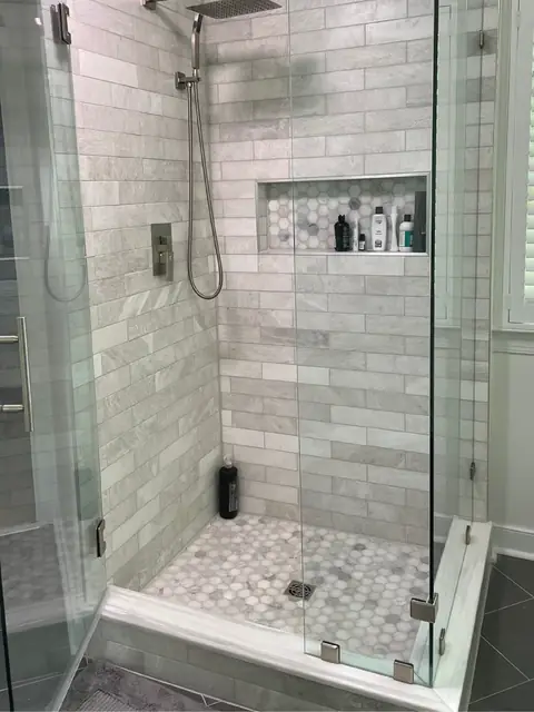 Walk-in shower with marble subway tile, a niche and a hexagon floor