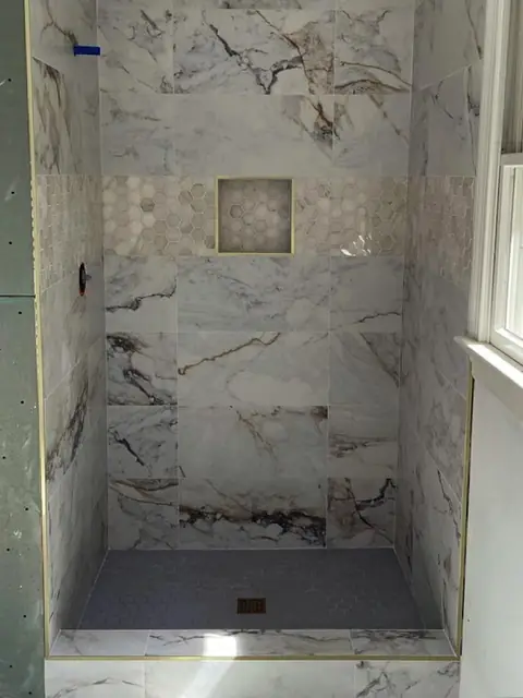 Marble-look tile shower with a mosaic niche