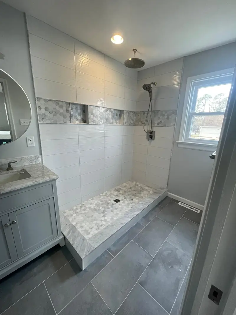 Tiled shower with a mosaic band and a pebble shower floor