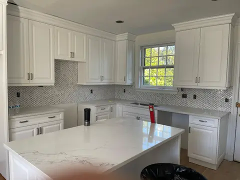 White kitchen with a tile backsplash and a quartz island